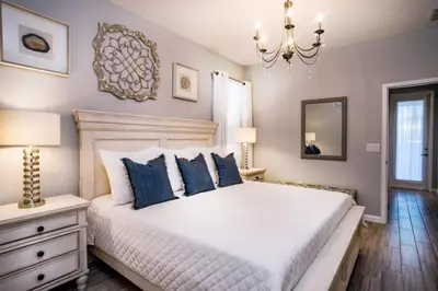 a bedroom with a bed with blue pillows and a chandelier at Flash 20 Off Gorgeous Vacation Home near Everywhere in Kissimmee
