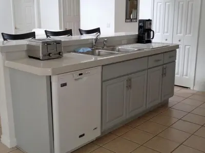 a kitchen counter with a sink and a microwave at Charming 4-Bedroom Villa with Pool & Spa, Only 15 Minutes from Disney! in Kissimmee
