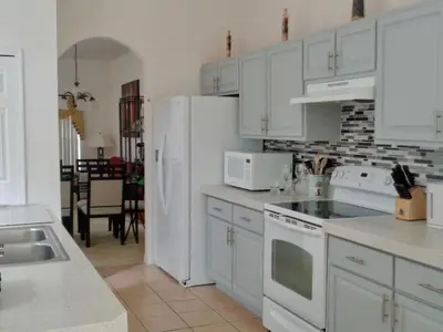 a kitchen with white cabinets and white appliances at Charming 4-Bedroom Villa with Pool & Spa, Only 15 Minutes from Disney! in Kissimmee