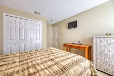 a bedroom with a bed and a table and a tv at Flash 20 Off Private Pool Home at Lake Berkley Resort in Kissimmee