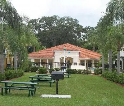 a group of picnic tables in the grass in front of a building at Flash 20 Off Private Pool Home at Lake Berkley Resort in Kissimmee