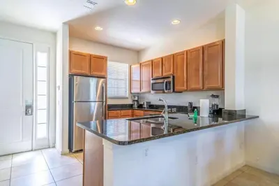 a kitchen with wooden cabinets and a stainless steel refrigerator at Flash 20 Off Private Spa Townhome at Regal Oaks Resort in Orlando