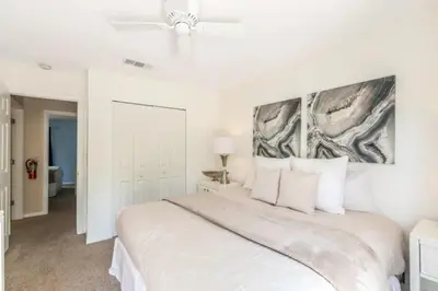 a white bedroom with a large bed with white pillows at Flash 20 Off Townhome at Emerald Island Resort in Kissimmee