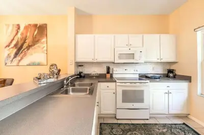 a kitchen with white cabinets and white appliances at Flash 20 Off Townhome at Emerald Island Resort in Kissimmee