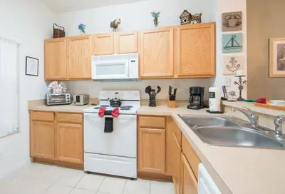 a kitchen with wooden cabinets and a white appliance at Flash 20 Off Townhome at Emerald Island in Kissimmee