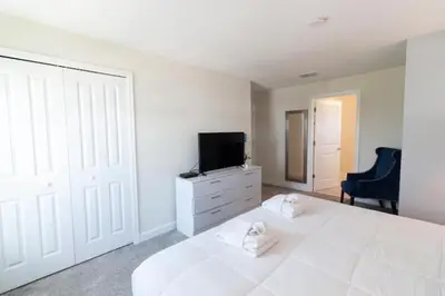 a bedroom with a white bed and a tv on a dresser at Flash 20 Sale Pvt Pool Townhome at Storey Lake in Kissimmee