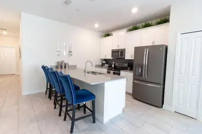 a kitchen with a counter with chairs and a refrigerator at Flash 20 Sale Pvt Pool Townhome at Storey Lake in Kissimmee