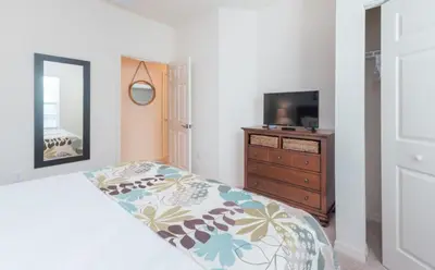 a bedroom with a bed and a dresser and a television at Special Offer Elegant Townhome at West Lucaya in Kissimmee