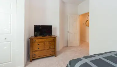 a bedroom with a tv on a wooden dresser at Special Offer Elegant Townhome at West Lucaya in Kissimmee