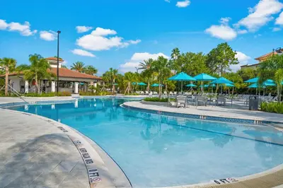 a swimming pool at a resort with blue umbrellas at New Modern Vista Cay Reserve Condo - 6006 in Orlando