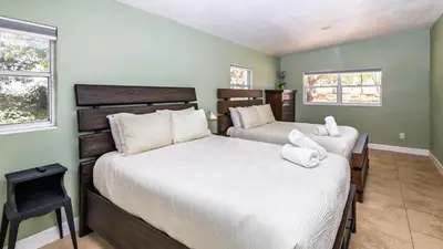 two beds in a room with green walls and windows at Lakefront Retreat - Boat - Fish - Close to all Orlando Parks - Disney - Universal - SeaWorld in Orlando