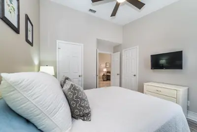 a bedroom with a white bed and a television at Special Offer Beautiful Pvt Pool home in Kissimmee