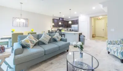 a living room with a blue couch and a kitchen at Special Offer Cozy Retreat at Compass Bay in Kissimmee