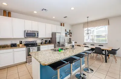 a kitchen with white cabinets and a island with bar stools at Special Offer Fantastic Townhome with Pvt Pool and Lake view near Disney in Kissimmee