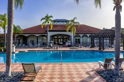 a resort swimming pool with chairs and palm trees at Special Offer Fantastic Townhome with Pvt Pool and Lake view near Disney in Kissimmee