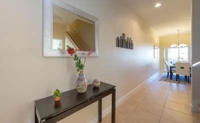 a living room with a table and a mirror at Special Offer Pvt Pool Townhome in Kissimmee