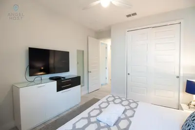 a white bedroom with a tv and a white door at Special Offer Pvt Pool and Spa Home at Encore in Orlando