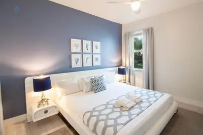 a bedroom with a large white bed with blue walls at Special Offer Pvt Pool and Spa Home at Encore in Orlando