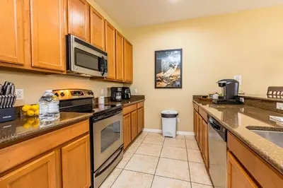 a kitchen with wooden cabinets and a stove top oven at Special Offer Stunning TownHome With Private Pool close to Disney 8960PP in Kissimmee