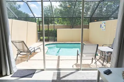 a swimming pool with two chairs and a table at New Luxury Disney Townhome at Windsor Hills Resort, 3BED 3BATH, Private Pool Parking WiFi Included in Orlando