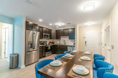 a kitchen with a wooden table and blue chairs at Special Offer Stylish Apartment at Vista Cay in Orlando