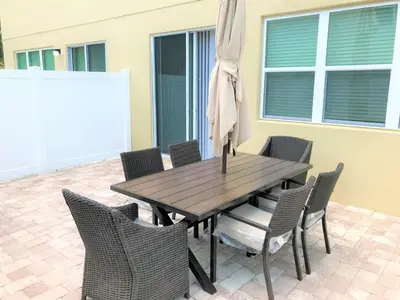 a wooden table with chairs and an umbrella on a patio at Special Offer Townhome at Compass Bay in Kissimmee