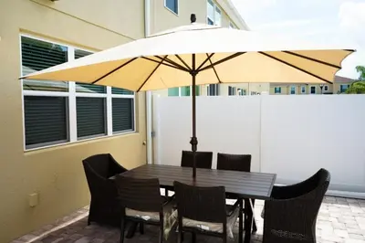 a wooden table with chairs and a large umbrella at Special Offer Townhome at Compass Bay in Kissimmee