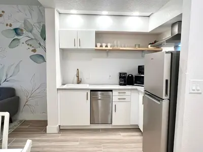 a small kitchen with white cabinets and a refrigerator at Condo close to Epic Universe - free parking in Orlando