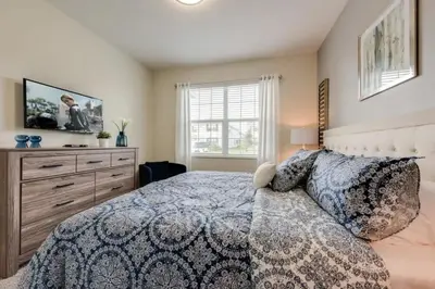 a bedroom with a bed and a dresser and a television at Casa Luxuosa 5Q c/ Piscina Perto da Disney! in Kissimmee