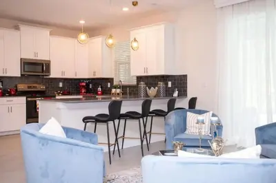 a kitchen with white cabinets and blue chairs at Casa 6Q de Alto Padrão c/ Game Room & Piscina in Kissimmee