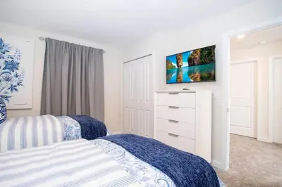 a bedroom with two beds and a tv on the wall at Casa 6Q de Alto Padrão c/ Game Room & Piscina in Kissimmee