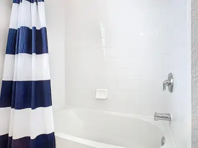 a white bathroom with a blue and white shower curtain at Windsor Hills Amazing 3BR Condo,Pool,Slides,Disney in Orlando