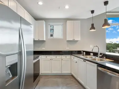 a kitchen with white cabinets and a stainless steel refrigerator at Modern 3 bedroom condo in downtown w free parking in Orlando