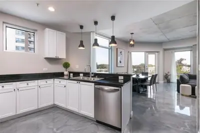 a kitchen with white cabinets and a dining room with a table at Modern 3 bedroom condo in downtown w free parking in Orlando