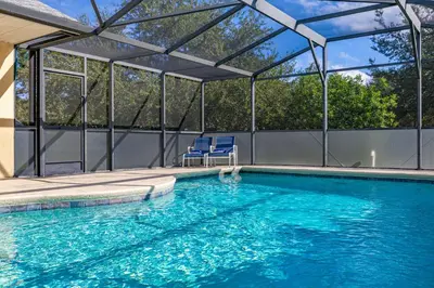 a swimming pool with two blue chairs in a pavilion at 373 - Stunning 4 Bedroom Villa with own Private South East Facing Pool in Orlando