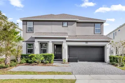 a house with a driveway and a garage at Upstay Vibrant Home w Themed Rooms Pool & Games in Kissimmee