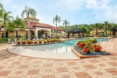 a pool at a resort with flowers in a courtyard at Upstay Vibrant Home w Themed Rooms Pool & Games in Kissimmee