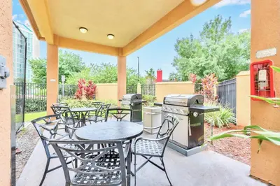 a patio with tables and chairs and a grill at Peaceful King Bed Apartment w Hot Tub & Pool in Orlando