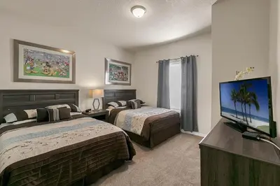a hotel room with two beds and a flat screen tv at Casa 3Q Lucaya – 10 Min da Disney c/ Clubhouse in Kissimmee