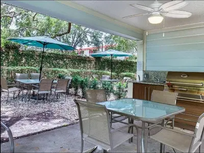 a patio with a table and chairs and umbrellas at Casa 3Q Lucaya – 10 Min da Disney c/ Clubhouse in Kissimmee