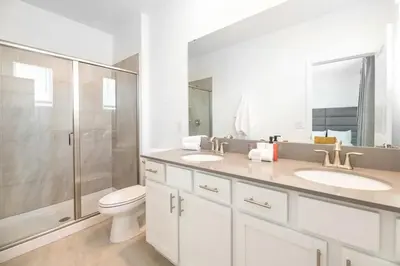 a bathroom with a toilet and two sinks and a shower at Casa de 6 Quartos no Storey Lake perto da Disney in Kissimmee