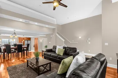 a living room with a leather couch and a dining room at Sunny Sales - Renovated TownHome by Disney! in Orlando