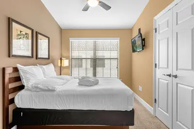 a bedroom with a bed with a ceiling fan and a window at Sunny Sales - Renovated TownHome by Disney! in Orlando