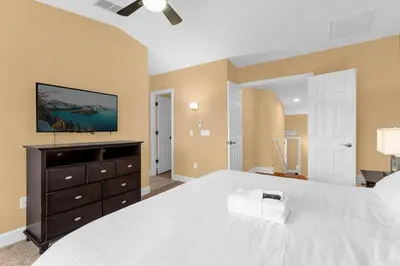 a bedroom with a large white bed and a dresser at Sunny Sales - Renovated TownHome by Disney! in Orlando