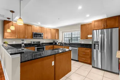 a kitchen with wooden cabinets and a stainless steel refrigerator at Sunny Sales - Renovated TownHome by Disney! in Orlando