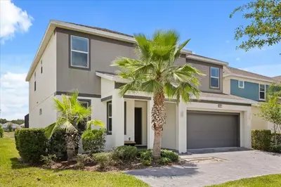 a house with two palm trees in front of it at Summer Deal - Amazing 8BR Home with Private Pool! in Kissimmee
