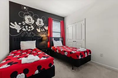 a bedroom with two beds and a wall with mickey mouse on it at Summer Deal - Amazing 8BR Home with Private Pool! in Kissimmee
