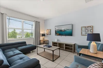 a living room with blue couches and a table at Summer Deal - Amazing 8BR Home with Private Pool! in Kissimmee