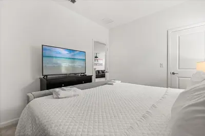 a white bedroom with a bed and a flat screen tv at Summer Deal - Amazing 8BR Home with Private Pool! in Kissimmee