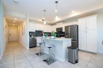 a kitchen with white cabinets and a large island with bar stools at Family Condo 2Bd Close to Disney at Storey Lake Resort in Kissimmee
